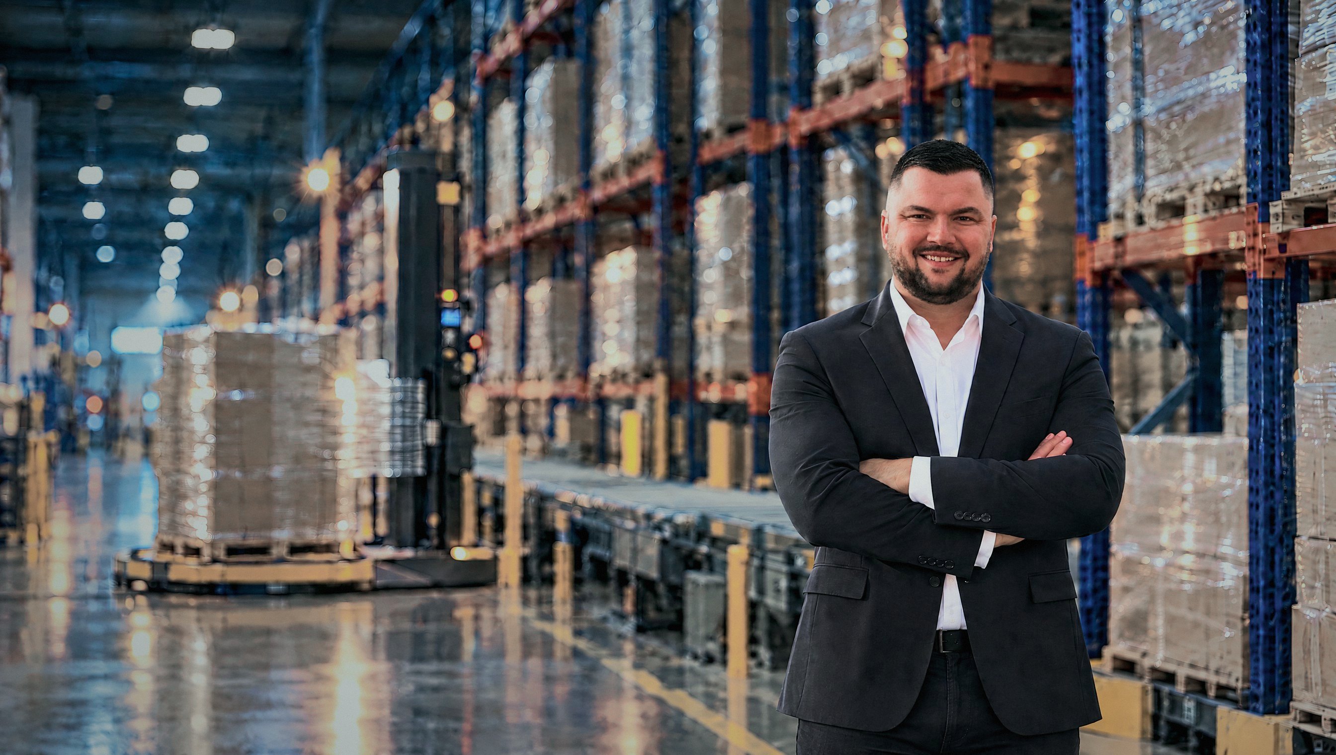 Mike Van Steenburgh in a packaging warehouse beside a stretch wrapper
