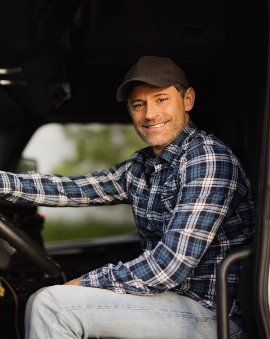 Smiling Packaging Exchange driver in the cab of a truck
