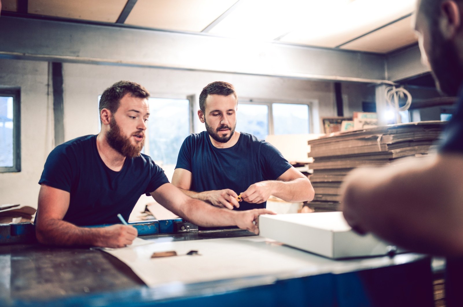 Packaging Exchange team members measuring and marking up a box sample at a sample table